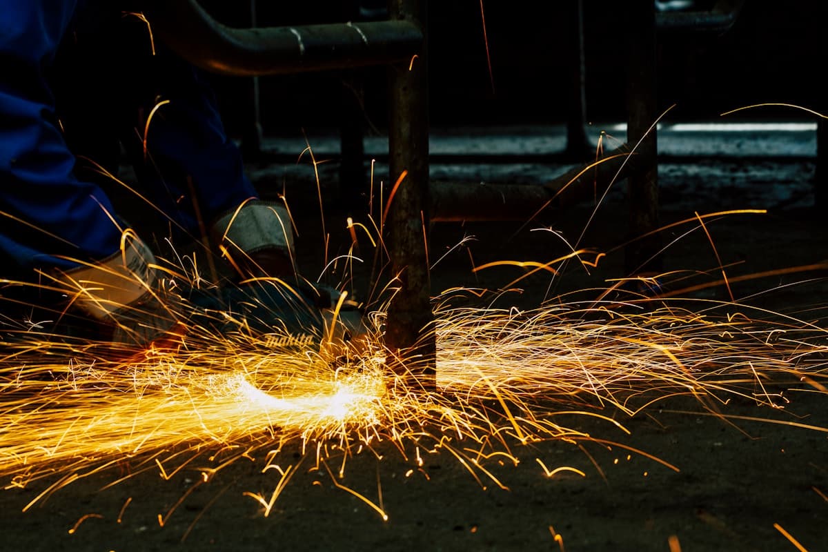 Maintenance technician grinding metal on industrial factory floor